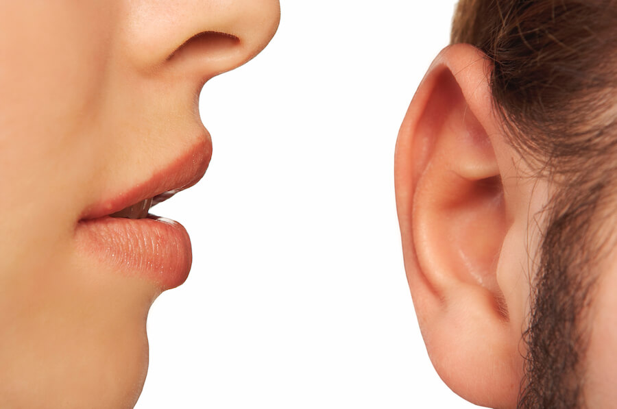 Close-up of a woman speaking into man's ear