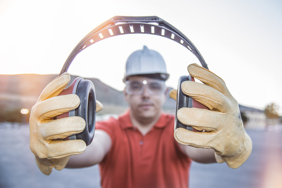 A man in a hard hat presenting some ear defenders