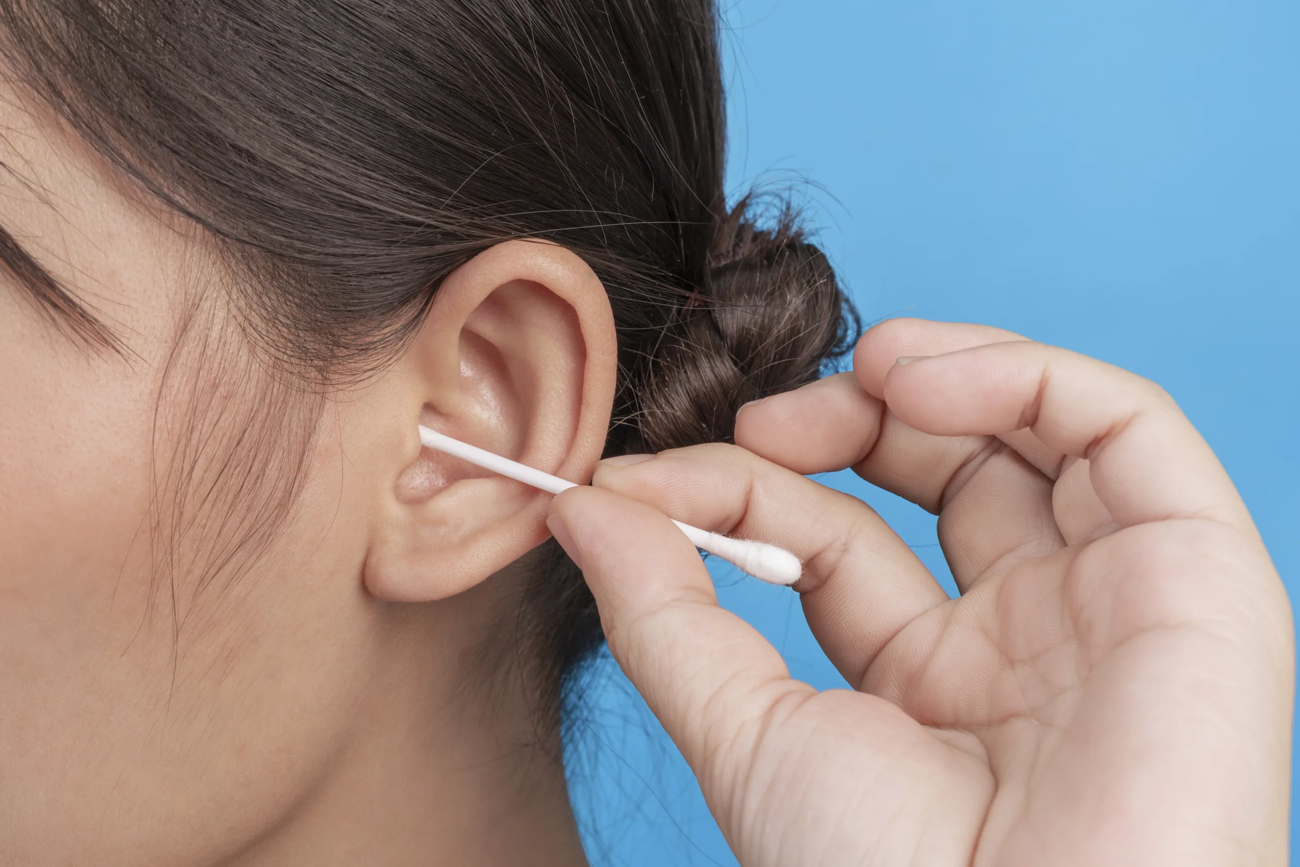 Cleaning ear with cotton swab.