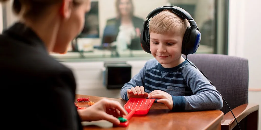 Child with headphones smiling.