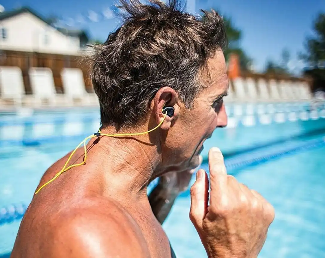Man with earplugs by pool.