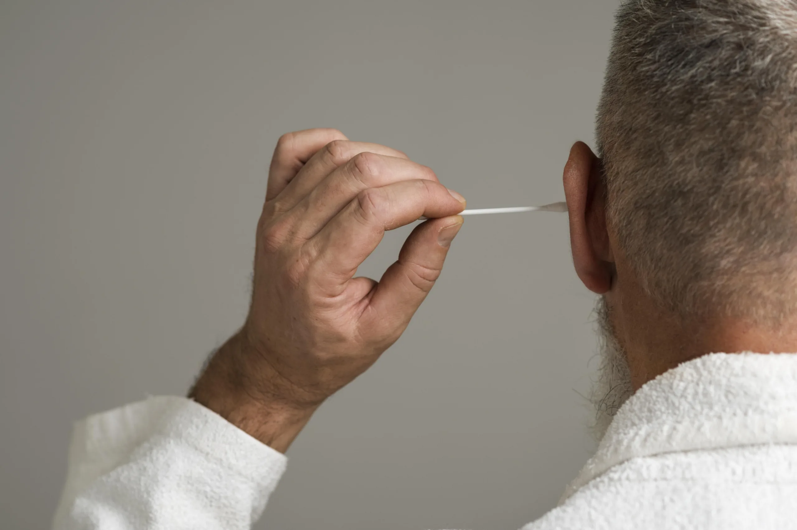 Man cleaning ear with swab.