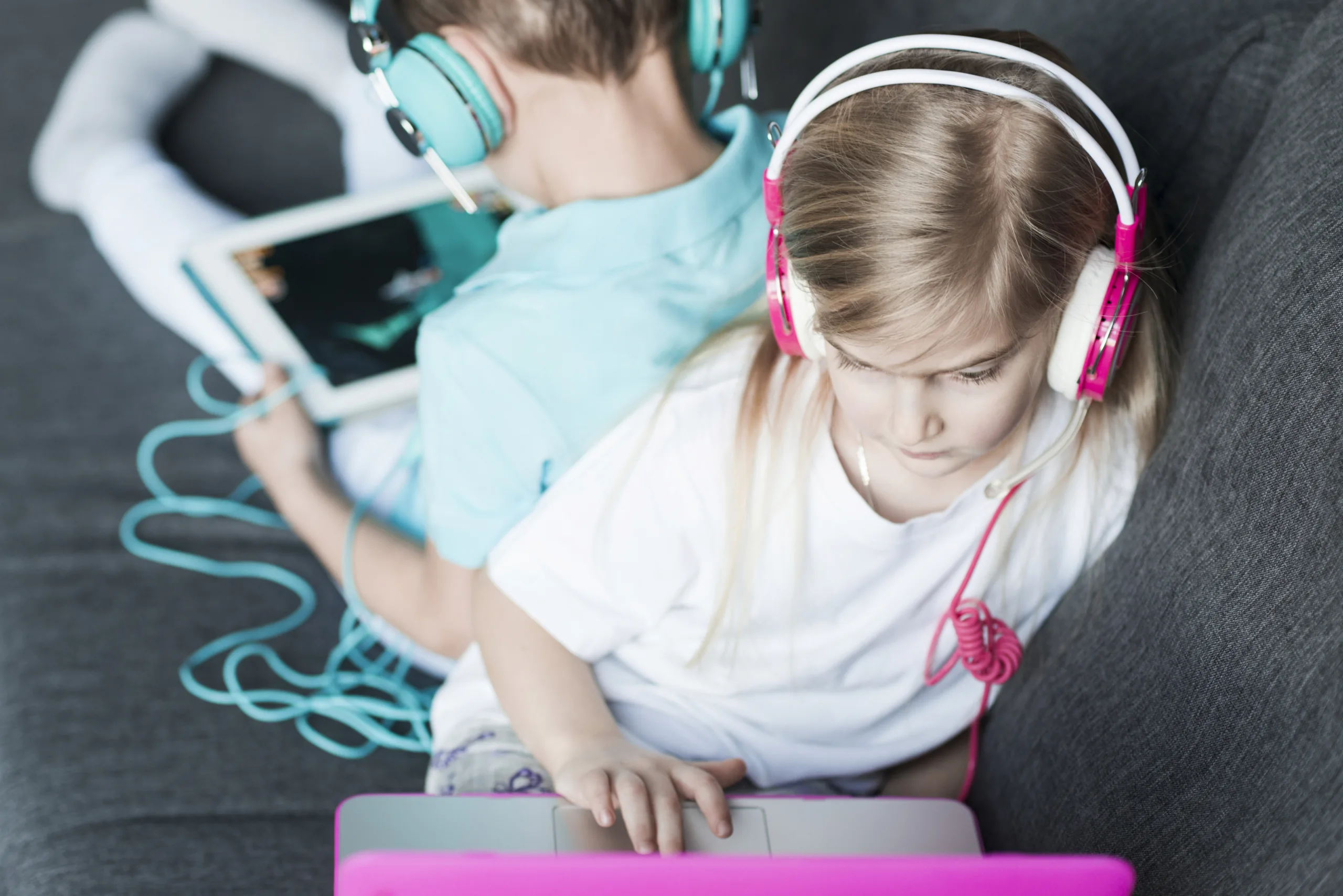 Children with headphones using devices.