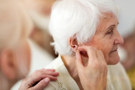 Woman adjusting hearing aid.