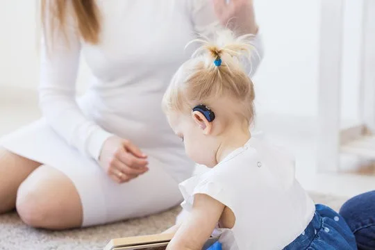 Child with hearing aid reading.