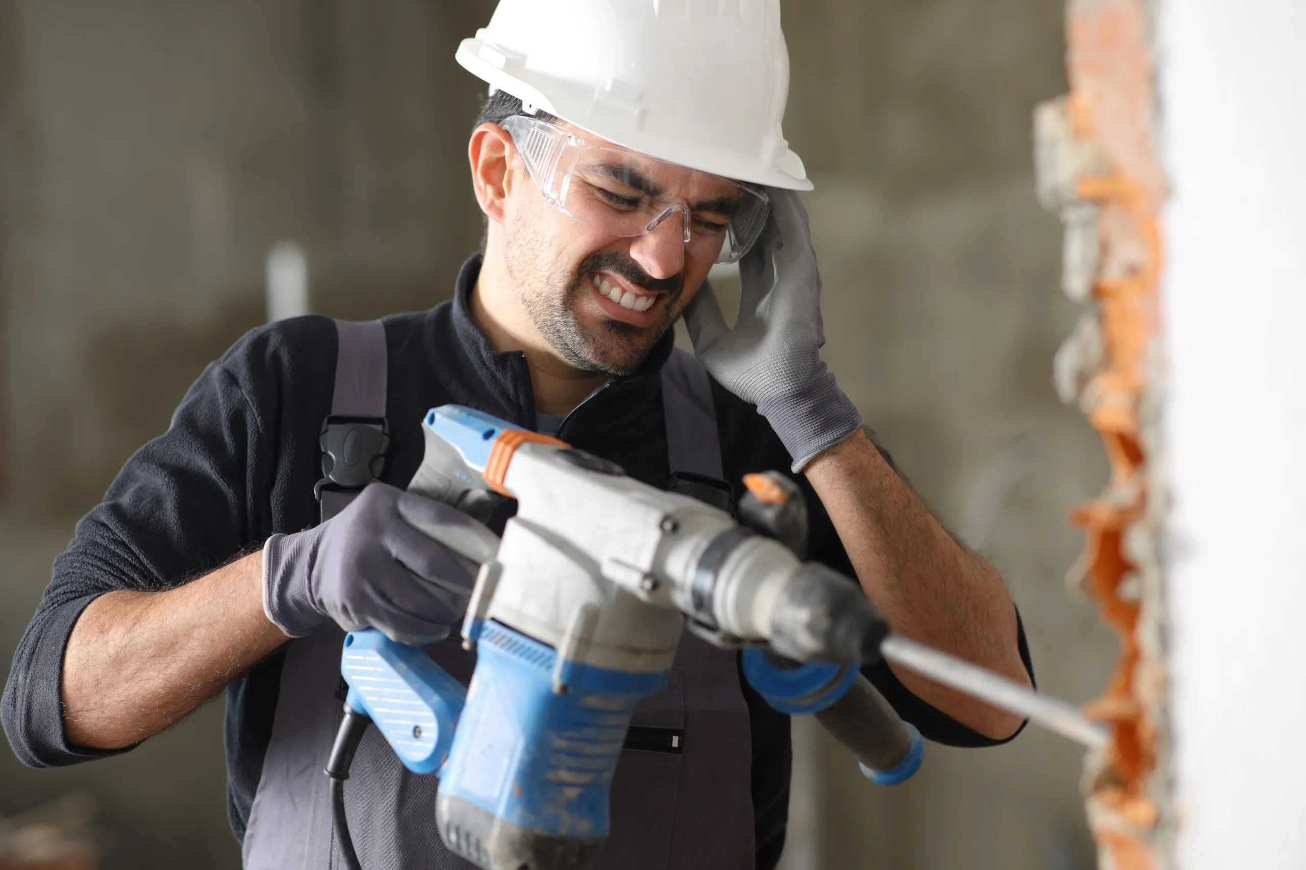 Worker using jackhammer, grimacing.