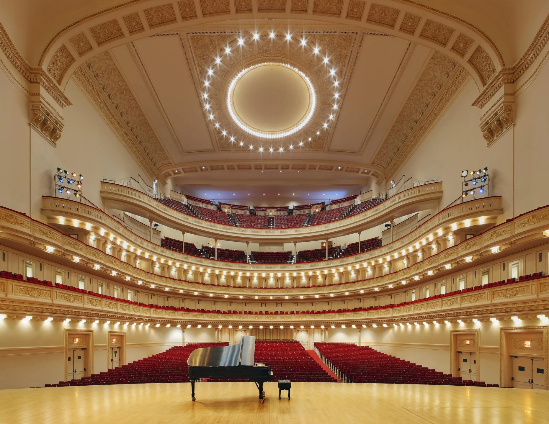 A grand piano sits on stage in an empty
