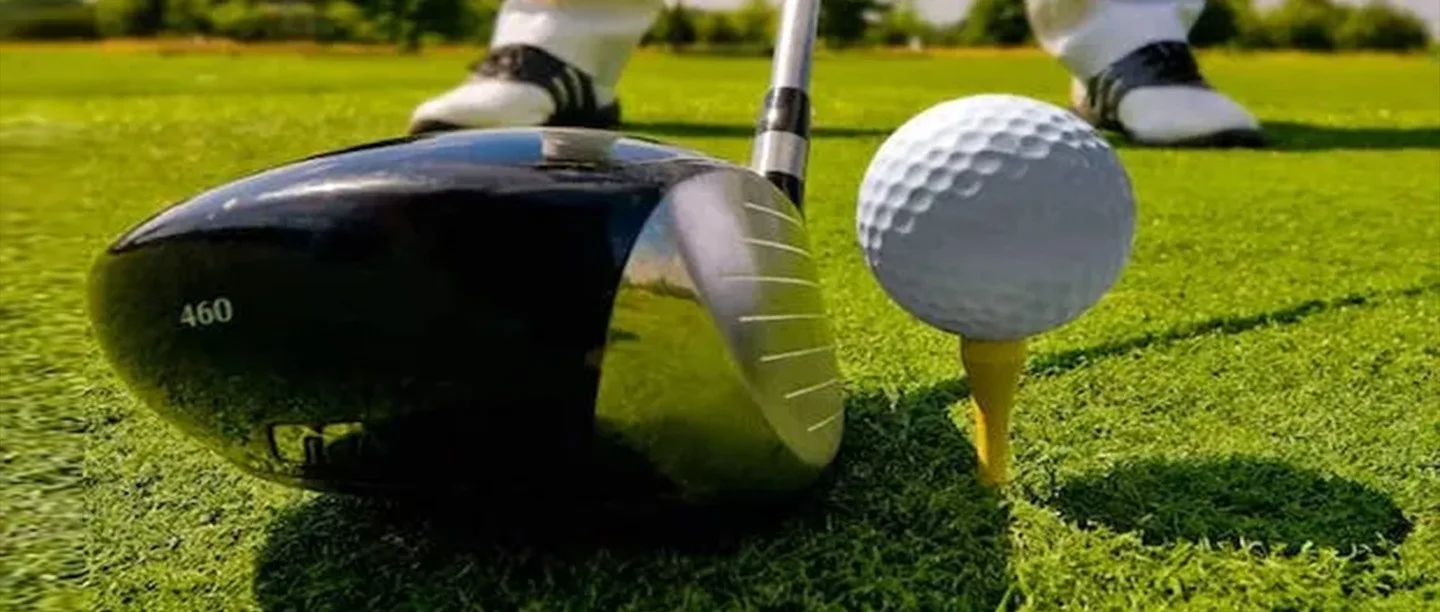 Close-up of a golf driver and ball on a tee. The question being asked is are golf drivers bad for your hearing?